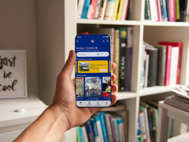 photographie d'une main tenant un smartphone avec l'application MaBibli ouverte